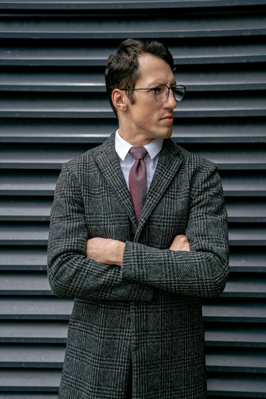 a man in a suit and tie standing with his arms crossed, inspired by Harrington Mann, unsplash, renaissance, tweed colour scheme, adam driver, wearing a suit and glasses, sports jacket