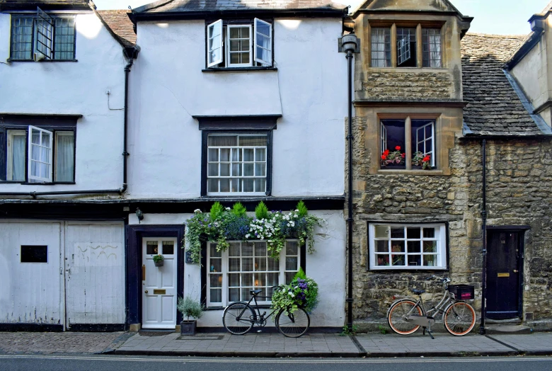 a couple of bikes parked in front of a building, by David Simpson, pexels contest winner, arts and crafts movement, little cottage, narrow, staggered terraces, daniel oxford