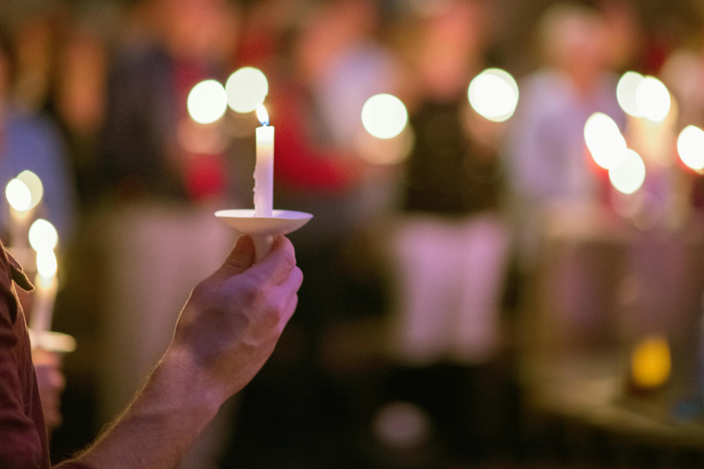 a man holding a lit candle in front of a group of people, profile image