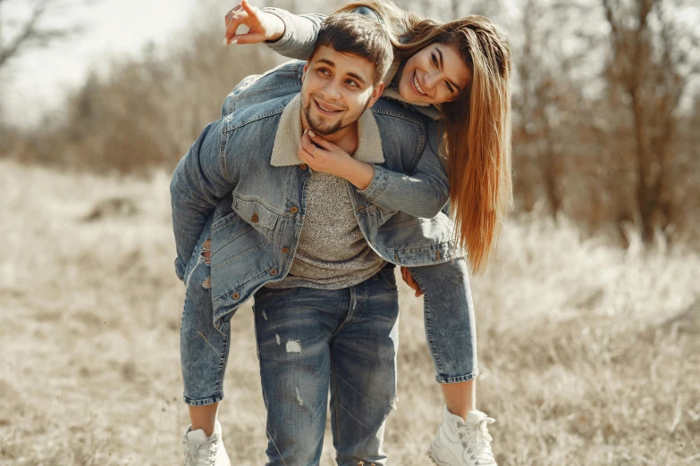 a man carrying a woman on his back in a field, trending on pexels, an aviator jacket and jorts, happy friend, ukrainian, wearing jeans