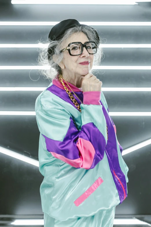 a woman standing in front of a neon light, gray haired, wearing a fancy jacket, with square glasses, wearing a track suit