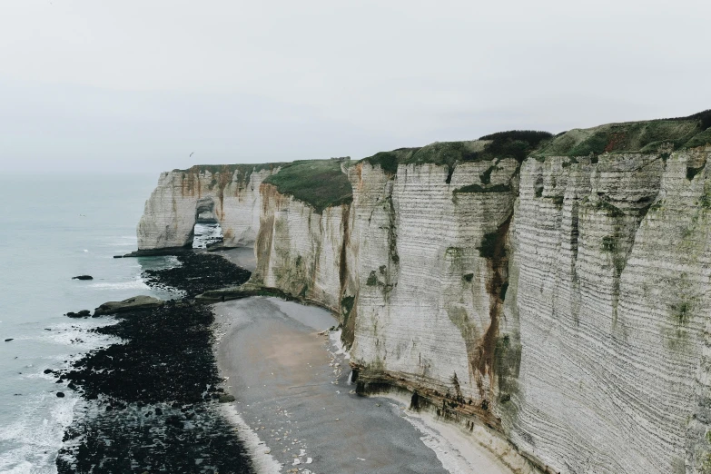 a man standing on top of a cliff next to the ocean, pexels contest winner, les nabis, the normandy landings, limestone, bella poarch, over a chalk cliff