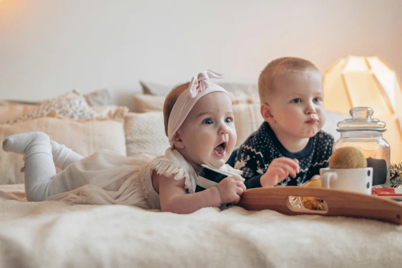 a couple of babies laying on top of a bed, pexels contest winner, happening, eating chips and watching tv, on a wooden tray, ellie victoria gale, beautiful high resolution