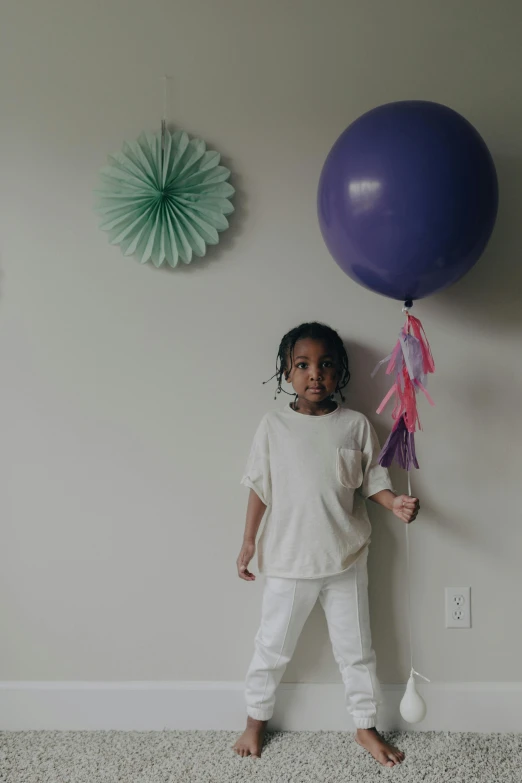 a little girl standing in front of a purple balloon