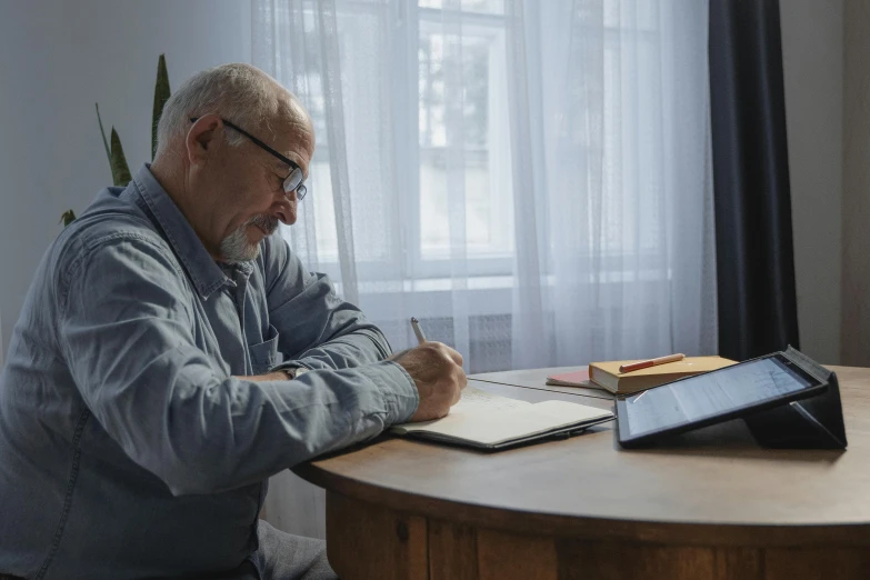 a man sitting at a table writing on a piece of paper, profile image, an oldman, thumbnail, computer