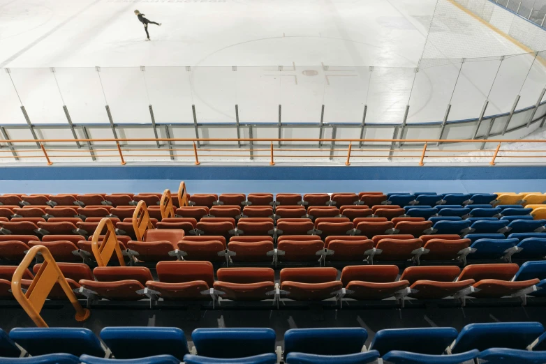 a hockey rink with rows of empty seats, a portrait, inspired by Andreas Gursky, unsplash contest winner, single figure, orange and blue, bench, no - text no - logo