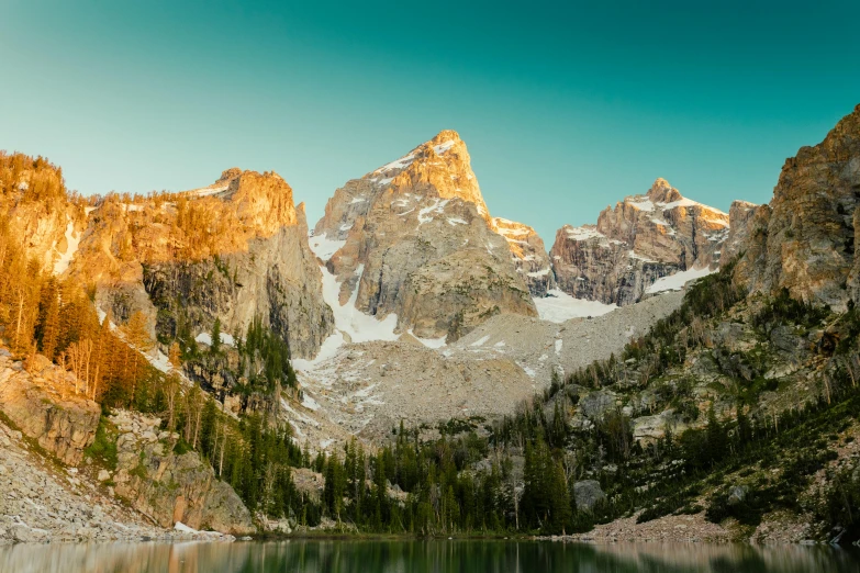 a lake with a mountain in the background, by Ethel Schwabacher, unsplash contest winner, tall spires, warm glow, big horn, high elevation