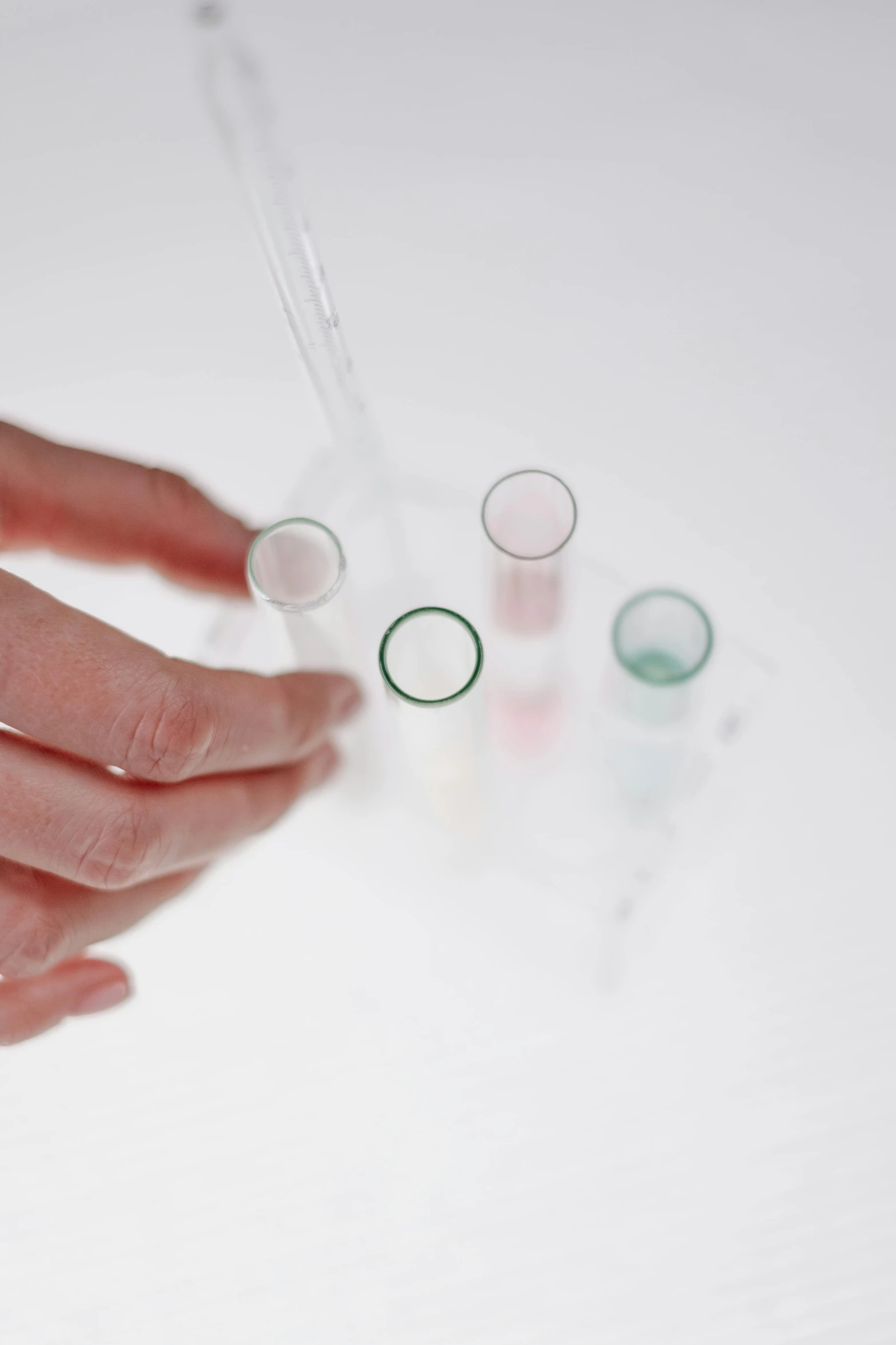 a close up of a person's hand holding a tube, beakers, with a white background, photographed for reuters, pink and blue and green mist