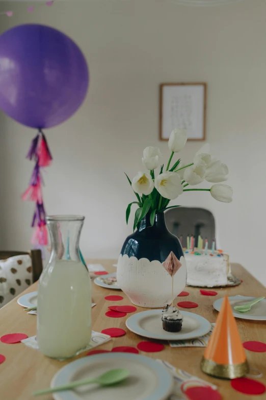 a wooden table topped with plates and a vase filled with flowers, by Arabella Rankin, unsplash, party balloons, wearing a party hat, purple accents, kids place