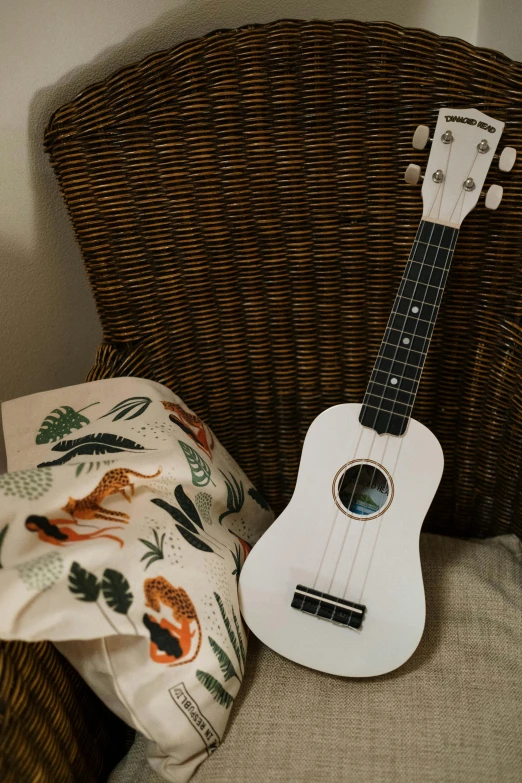 a ukulele sitting on top of a chair next to a pillow, white, product image, toys, throw