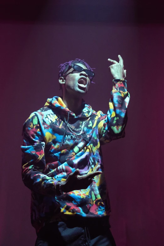 a man standing on top of a stage holding a microphone, an album cover, inspired by Zhu Da, pexels, visual art, wearing a purple sweatsuit, wearing an eyepatch, wearing a colorful coogi sweater, dramatic lighting; 4k 8k