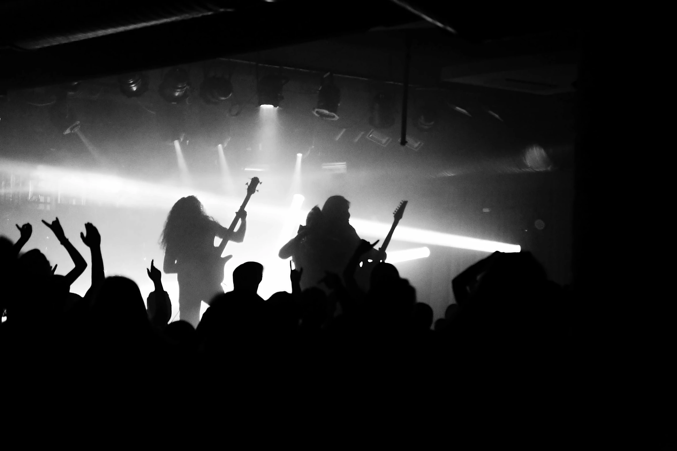 a group of people that are standing in front of a stage, a black and white photo, by Kristian Zahrtmann, pexels, black metal concert flyer, playing guitar onstage, siluette, gold and black metal