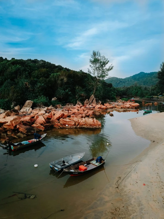 a boat sitting on top of a sandy beach, by Julia Pishtar, pexels contest winner, sumatraism, next to a small river, in style of joel meyerowitz, fishing town, floating rocks