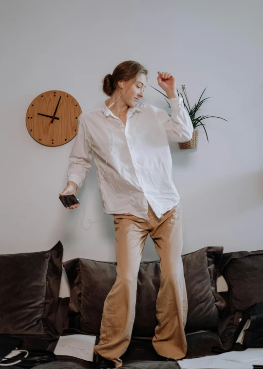 a woman standing on top of a couch in a living room, by Cosmo Alexander, trending on pexels, happening, he is dancing, wearing a linen shirt, dmitry prozorov style, phone photo