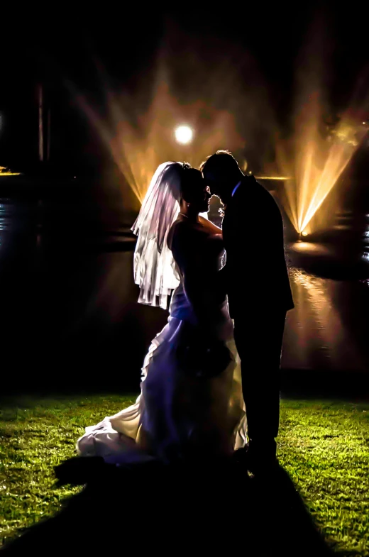 a bride and groom standing in front of a lake at night, dramatic stage lighting, sunny lighting, dramatic lighting - n 9, light show