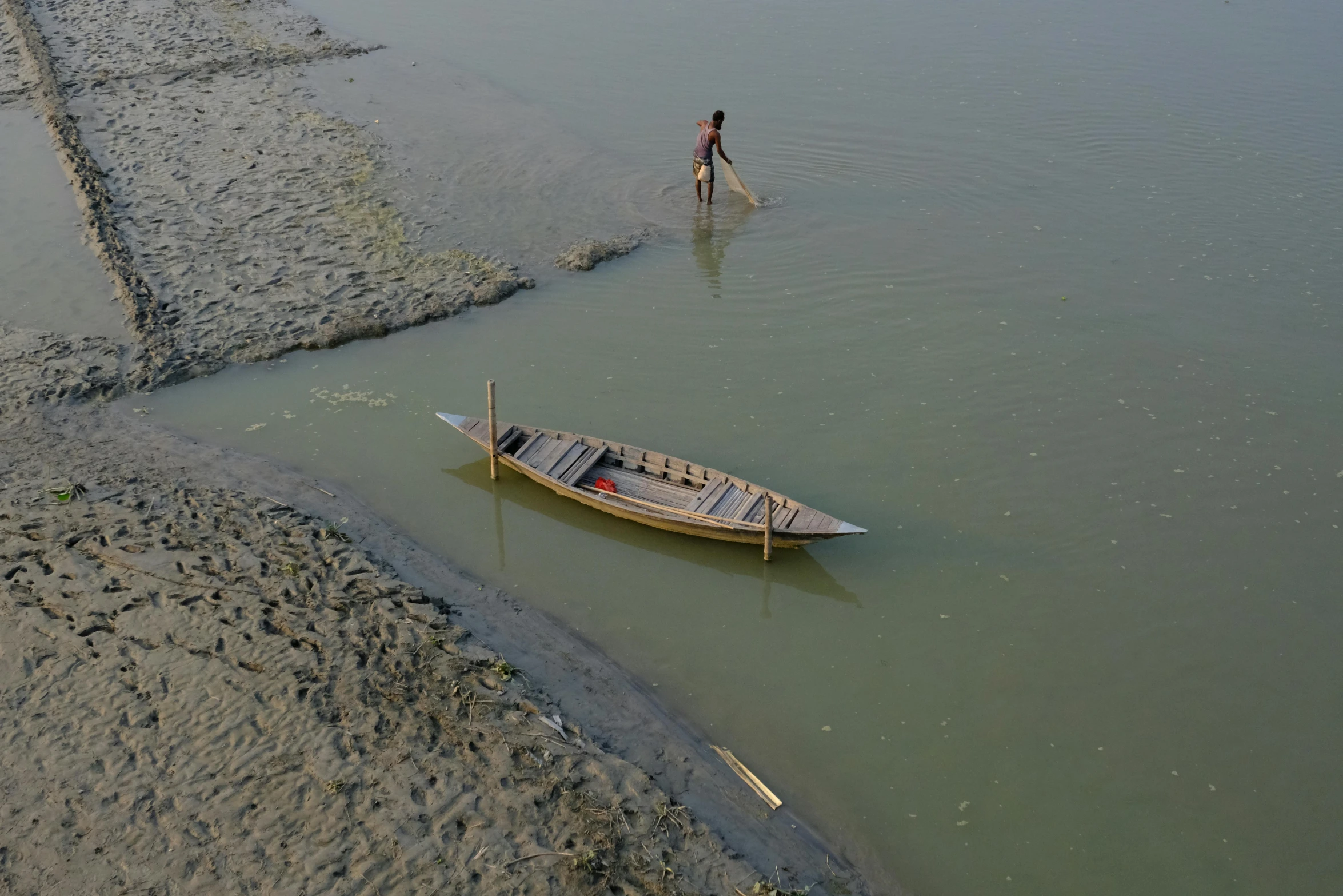 a man standing next to a boat in a body of water, by Sunil Das, slide show, great river, thumbnail, a high angle shot