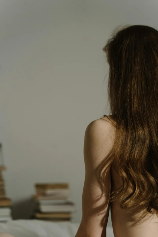 a naked woman sitting on top of a bed, inspired by Nan Goldin, trending on pexels, renaissance, hair : long brown, looking from behind, 4k', dynamic wavy hair