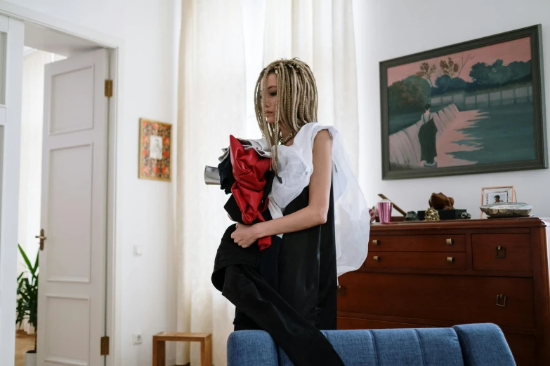 a woman standing on top of a blue couch, an album cover, inspired by Nan Goldin, pexels contest winner, visual art, realistic cloth puppet, black red white clothes, wearing jetpack, at home