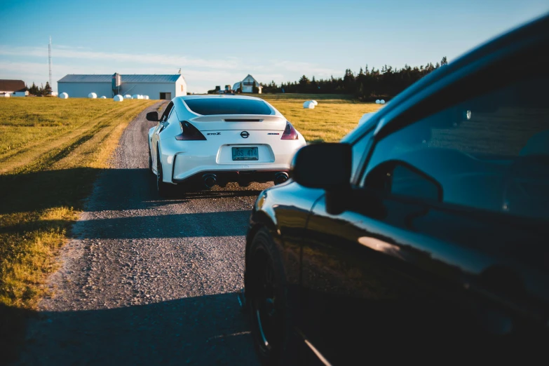 a white car driving down a road next to a black car, by Matt Cavotta, pexels contest winner, jdm, lined up horizontally, day setting, sports car