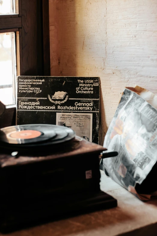 a record player sitting on top of a table next to a window, an album cover, by Sebastian Spreng, trending on unsplash, soviet interior, preserved historical, dusty library, musician