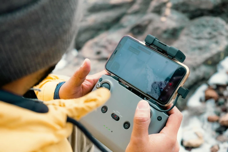 a close up of a person holding a cell phone, a picture, drone camera angle, cliffside, holding controller, phantom grip