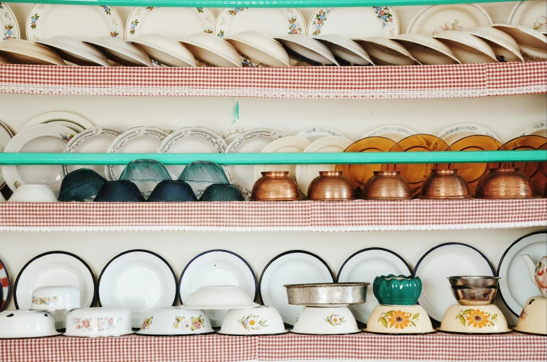 a shelf filled with lots of plates and bowls, by Pamela Ascherson, trending on unsplash, fan favorite, william eggleston, traditional corsican, lined up horizontally