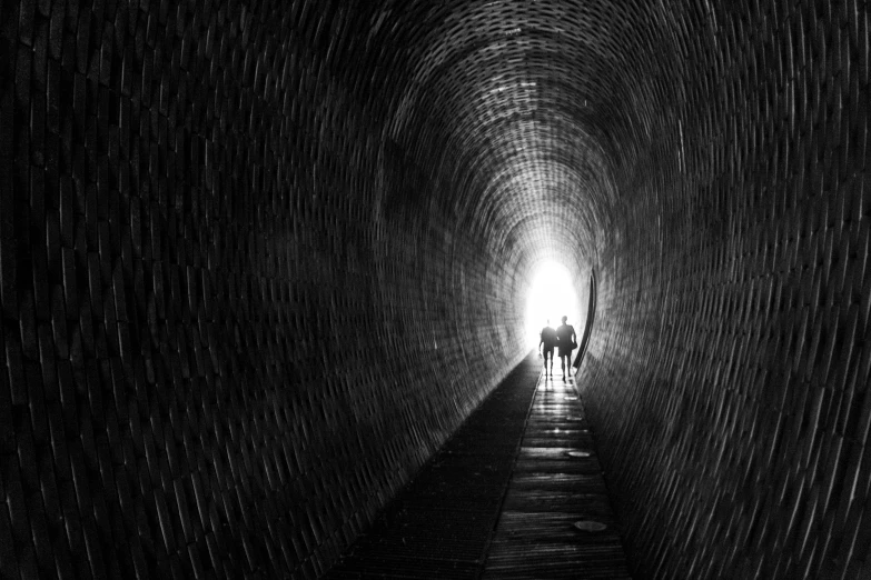 a black and white photo of a person walking through a tunnel, by Jan Rustem, pexels contest winner, couple, three, guys, rocket