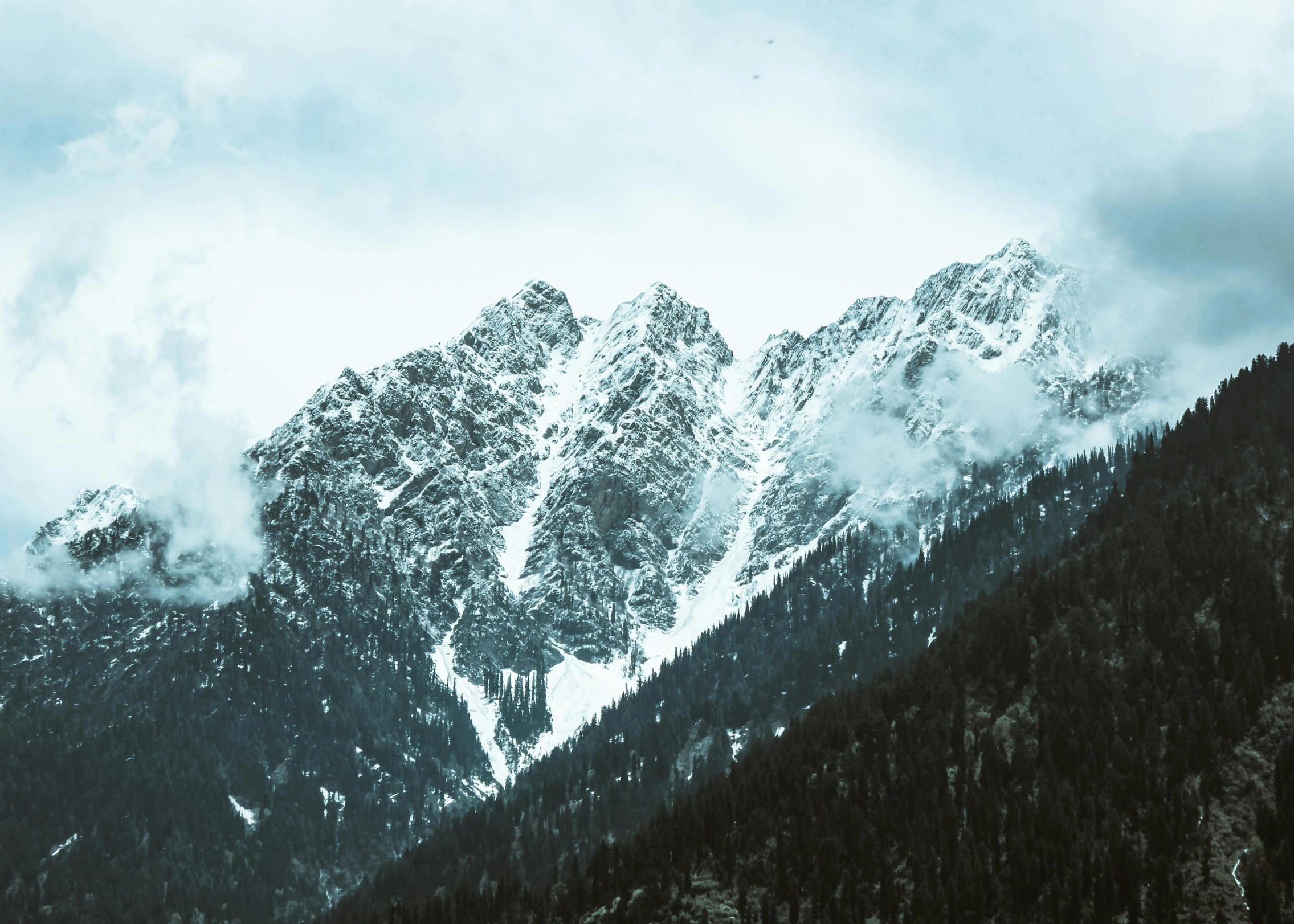 the mountains are covered in snow on a cloudy day, an album cover, pexels contest winner, trending on, teal aesthetic, multiple stories, slightly pixelated