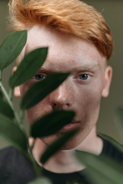 a close up of a person holding a plant, trending on pexels, hyperrealism, red haired teen boy, square masculine facial features, hr ginger, attractive man