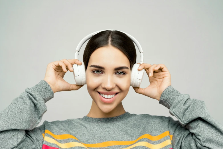 a woman with headphones covering her ears, trending on pexels, on grey background, avatar image, smiling into the camera, uploaded