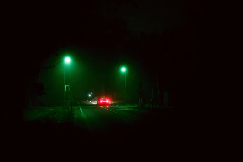 a car driving down a dark street at night, a picture, inspired by Elsa Bleda, realism, green bright red, ((mist)), street light, 2022 photograph