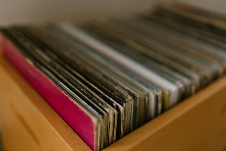 a stack of vinyl records sitting on top of a wooden table, by Attila Meszlenyi, unsplash, vhs artefacts, on a wooden tray, in a row, zoomed in