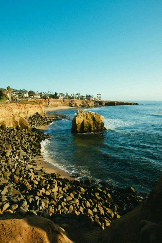 a man riding a surfboard on top of a rocky beach, the city of santa barbara, slide show, tall spires, travel