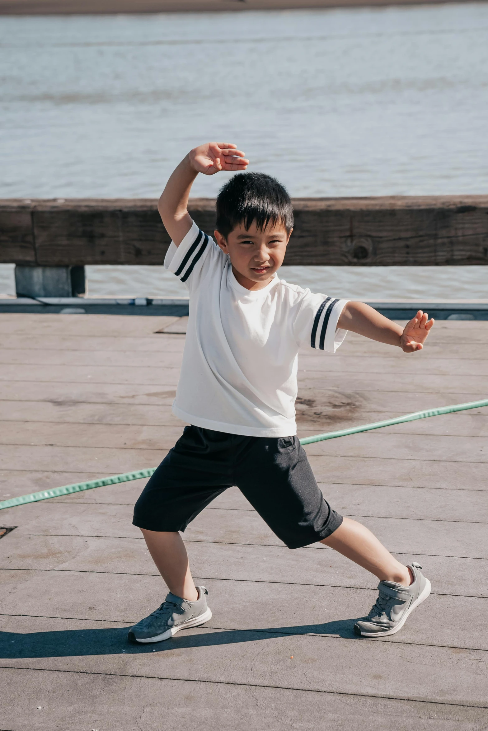 a young boy holding a tennis racquet on a tennis court, inspired by Liang Kai, pexels contest winner, happening, near a jetty, he is dancing, wearing a tee shirt and combats, hero pose