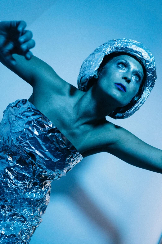 a woman in a silver dress holding a tennis racquet, a surrealist sculpture, unsplash, bauhaus, blue holographic face, contemporary dance, wearing a space suit, concert