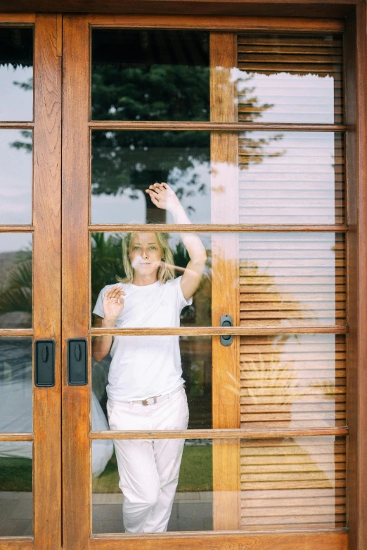 a woman standing in front of a wooden door, sliding glass windows, amber heard, hollister ranch, waving