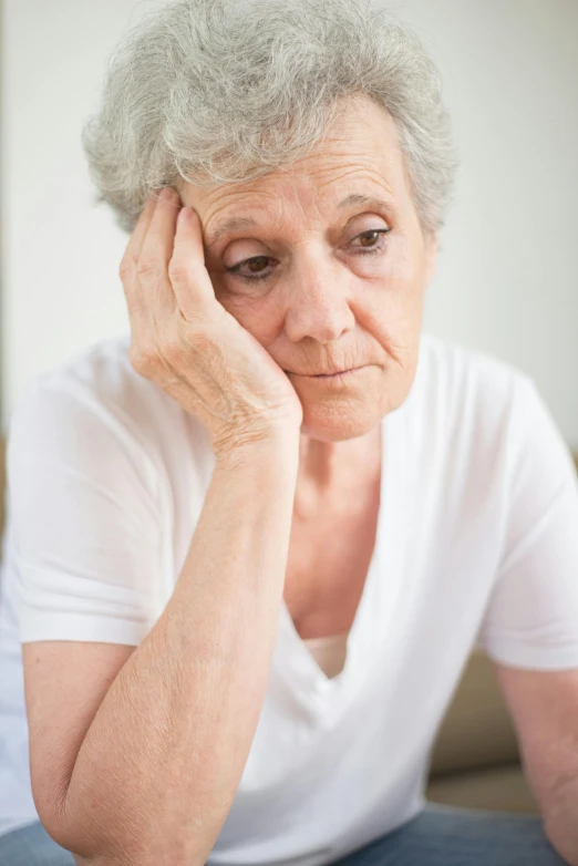 a woman sitting on a couch with her head in her hands, aging, sad eyebrows, photo of a woman, going gray