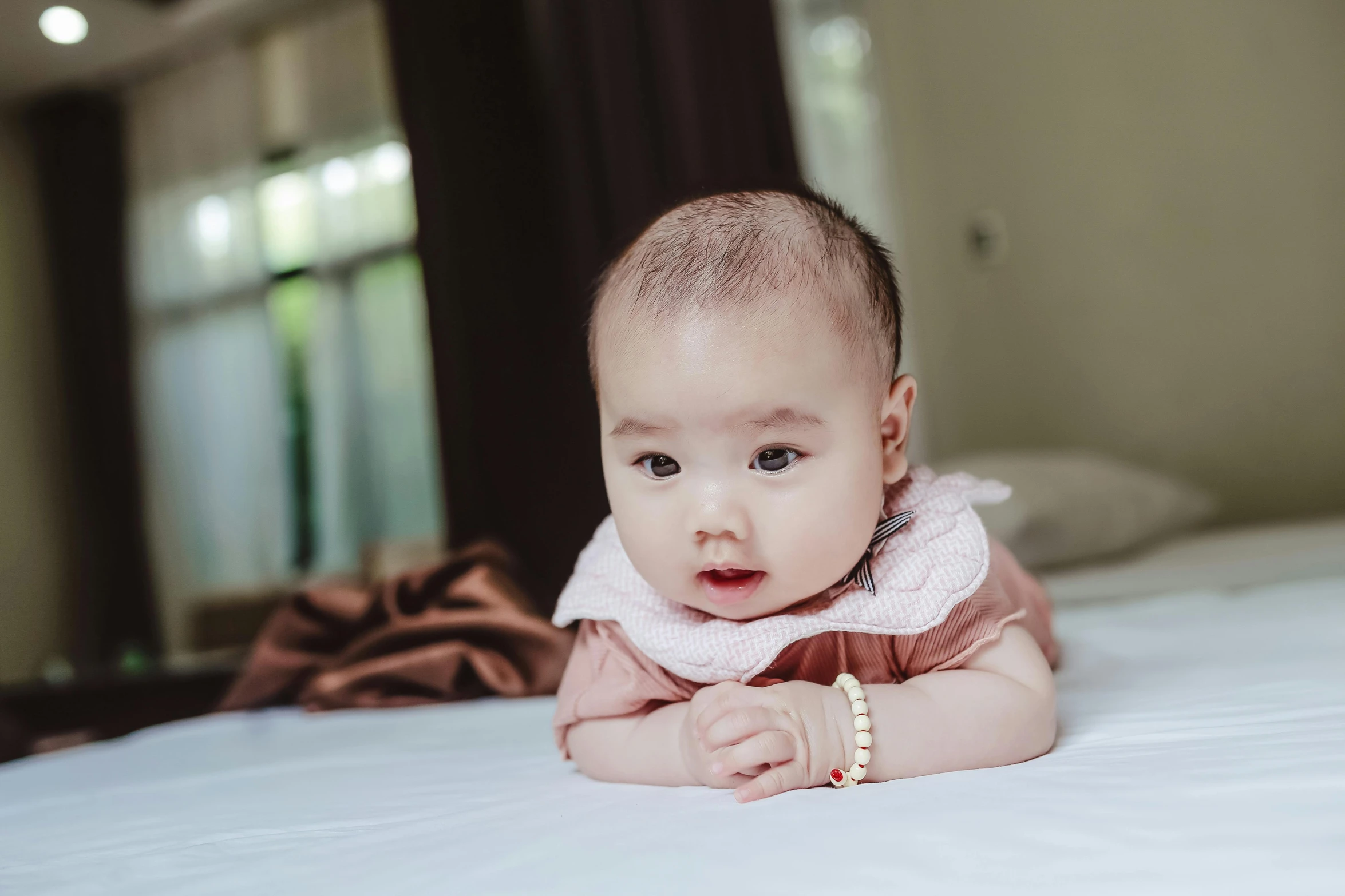 a close up of a baby laying on a bed, unsplash, happening, wearing elegant jewellery, korean girl, awkward, premium quality