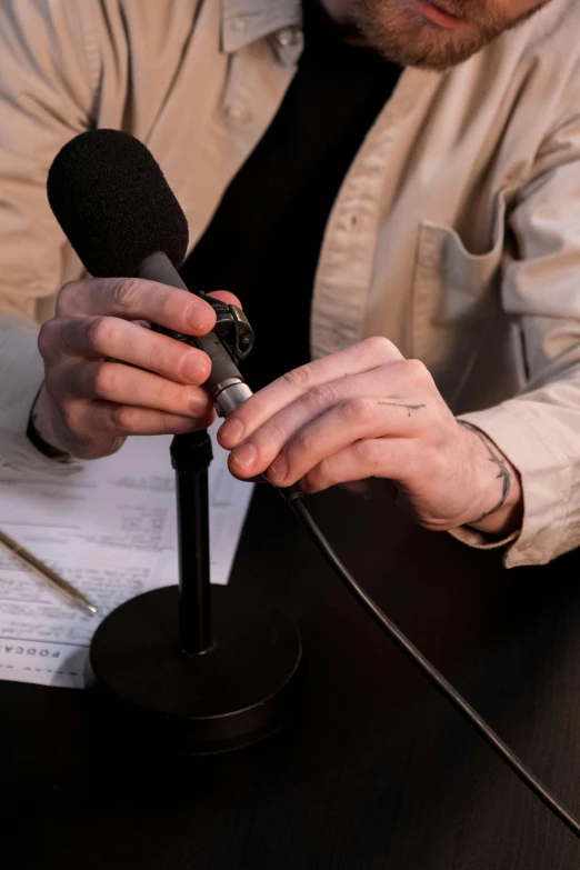 a man sitting at a table with a microphone, trending on reddit, private press, partially cupping her hands, studio photo, lgbtq, extra detail