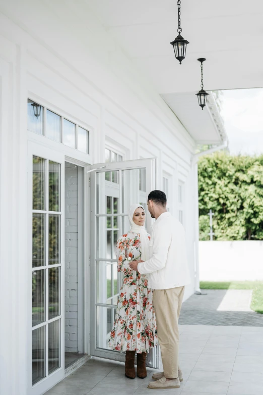a man and woman standing next to each other on a porch, unsplash, hurufiyya, in white room, hijab, pregnancy, lush surroundings