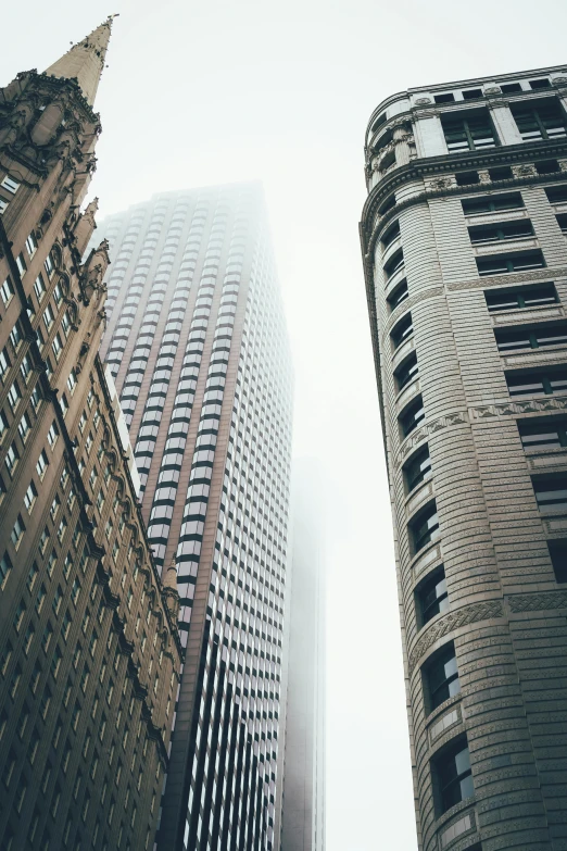 a couple of tall buildings sitting next to each other, a picture, by Dan Christensen, unsplash contest winner, gray fog, neo - classical, buildings are flying, looking left