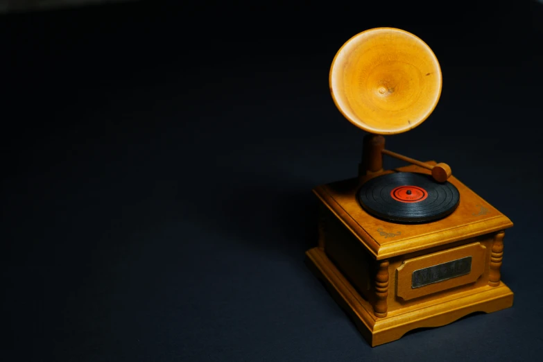 a wooden record player sitting on top of a table, in front of a black background, single horn, yellow, high-quality photo