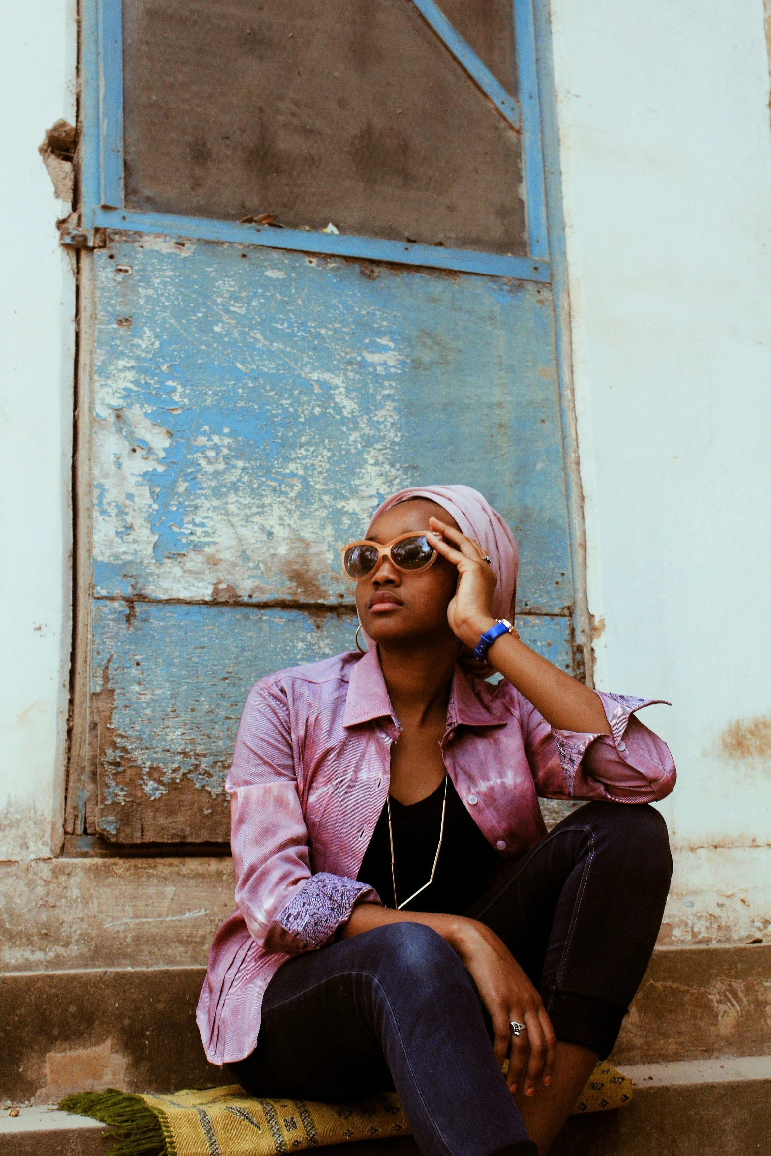 a woman sitting on a step talking on a cell phone, an album cover, by Ella Guru, trending on unsplash, afrofuturism, somalia, wearing shades, leaning on door, casual pose