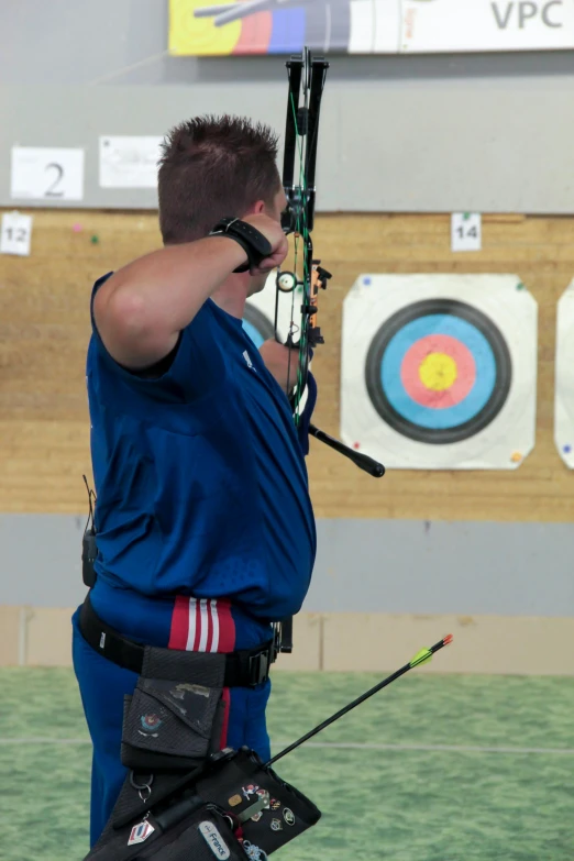 a man that is standing in the grass with a bow, competition highlights, indoor picture, christof romuald, profile image