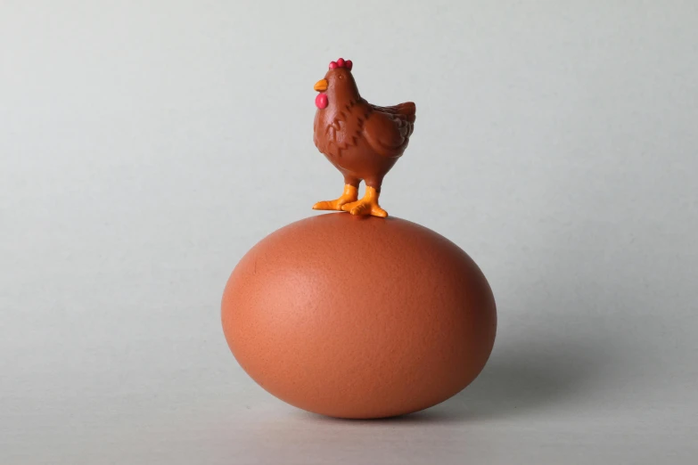 a toy chicken standing on top of an egg, a surrealist sculpture, inspired by Károly Patkó, brown, single figure, dezeen, hero pose