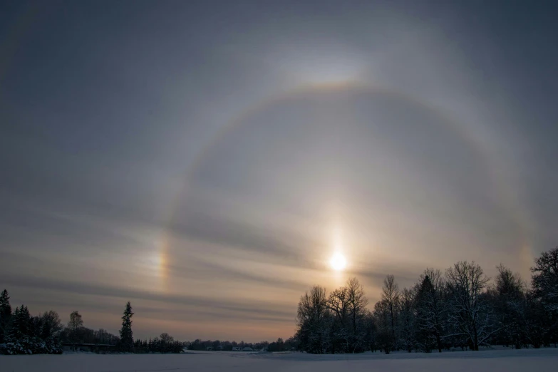 a snow covered field with a rainbow in the sky, by Jan Rustem, pexels contest winner, land art, two pure moons, glowing halo, during an eclipse, hyperdetailed photo