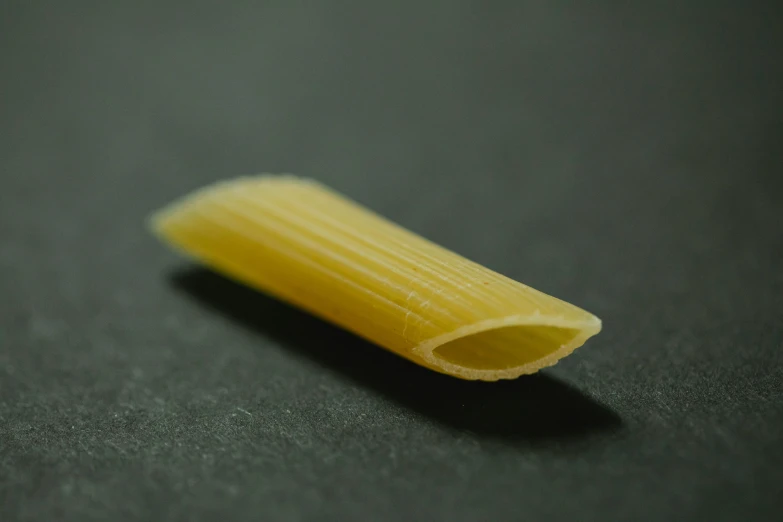 a piece of pasta sitting on top of a table, a macro photograph, non-pleated section, smooth oval head, product image, tubes