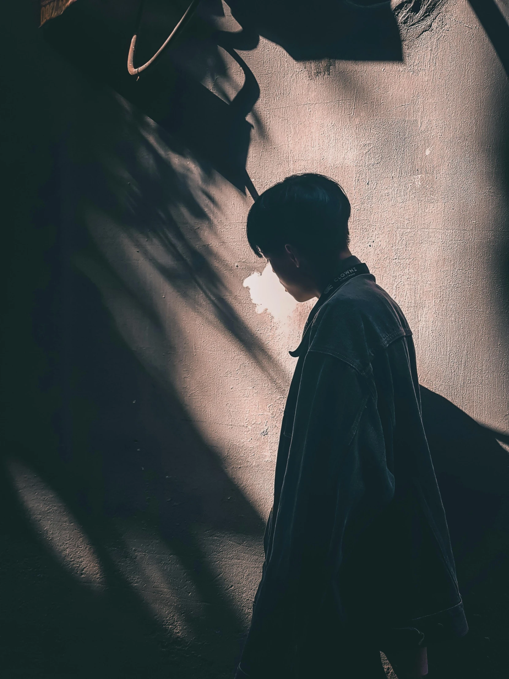 a man walking down a street in the dark, by Shang Xi, pexels contest winner, realism, sunlight filtering through skin, portrait of a japanese teen, thoughtful ), black cloak hidden in shadows