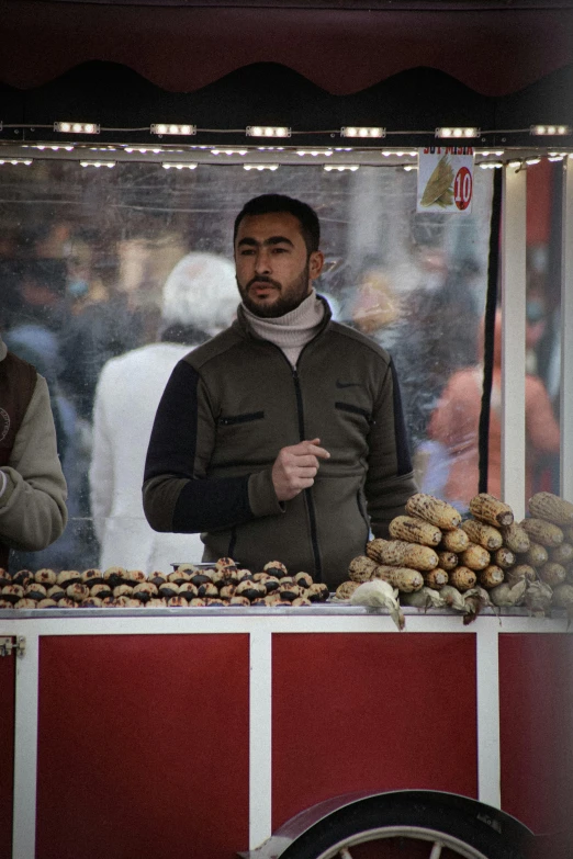 a man standing in front of a food stand, acorns, real life photo of a syrian man, breads, 2019 trending photo