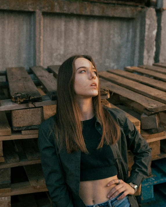 a woman standing in front of a pile of wood, inspired by Elsa Bleda, trending on pexels, aestheticism, portrait androgynous girl, looking off to the side, brown haired, stood in a factory